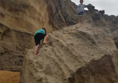 Climbing large rock at Loch Ard Gorge beach
